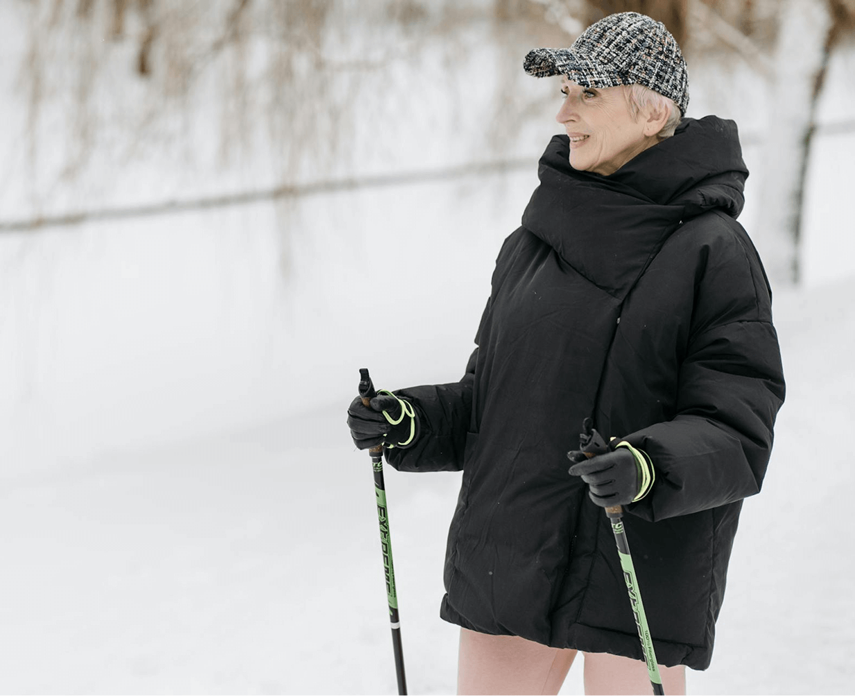 Une femme de soixante ans en tenue d'hiver lors d'un trek tenant des bâtons de marche.