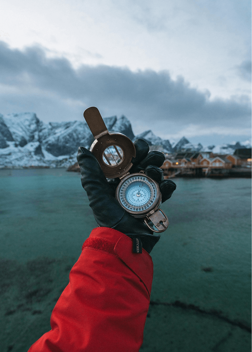 Le bras d'un homme tenant une boussole lors d'un trek aux îles lofoten en Norvège.